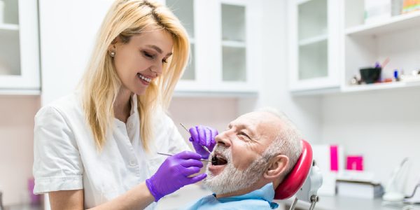 An Image Representing A Leading Dentist Giving Dental Treatmet To A Senior Citizen.