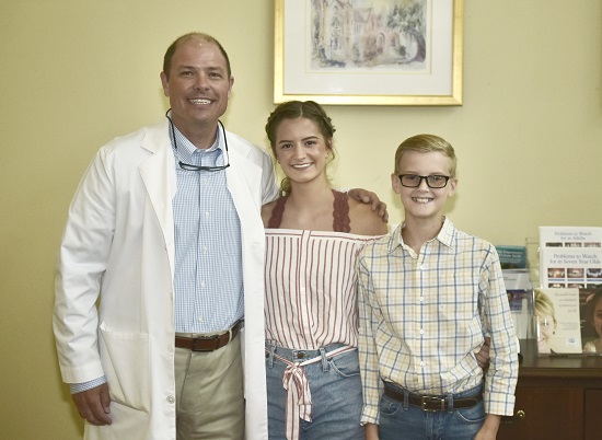 A doctor posing with two of his patients